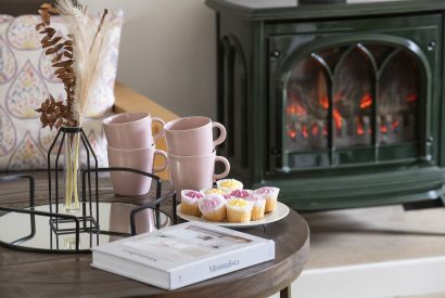 A coffee table with magazines in front of the log burner at Farmyard Cottage, Wiltshire