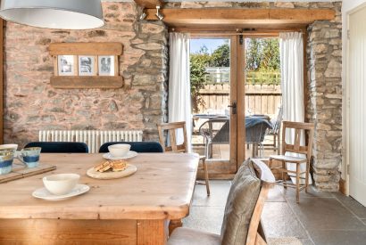 The dining table with doors onto the patio at Chapel Cottage, Pembrokeshire