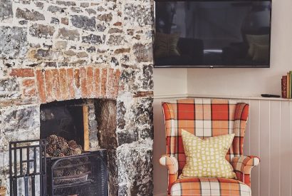 The single armchair beside the fireplace and Smart TV at Sunflower Cottage, Vale of Glamorgan