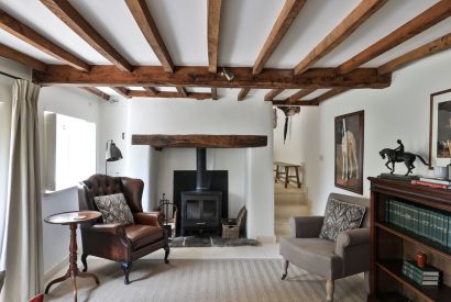 The living room with a log burner and oak beams at Rambling Rose Cottage, Cotswolds