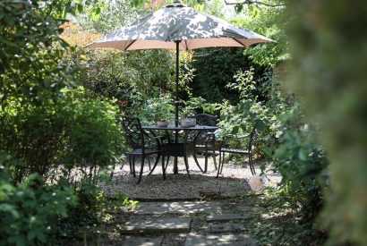 A dining table and parasol in the garden at Rambling Rose Cottage, Cotswolds 