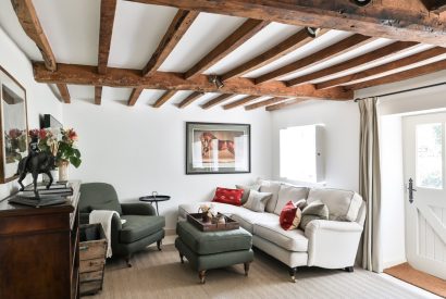 The cosy living room with a sofa and armchair at Rambling Rose Cottage, Cotswolds