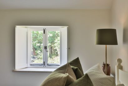 The window with pretty views in the master bedroom at Rambling Rose Cottage, Cotswolds