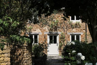 The honey-coloured stone exterior of Rambling Rose Cottage, Cotswolds