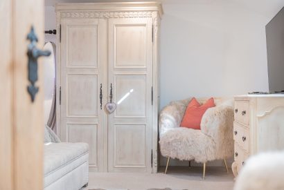 A single armchair and wardrobe in a king-size bedroom at Rose Walls, Lake District 