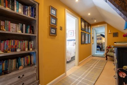 The hallway with book shelves leading to the bedrooms at Thatch Corner, Somerset