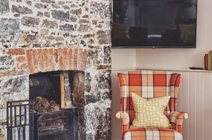 The single armchair beside the fireplace and Smart TV at Sunflower Cottage, Vale of Glamorgan