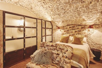 The king-size bedroom with exposed brick walls at Fritillaria Cottage, Vale of Glamorgan
