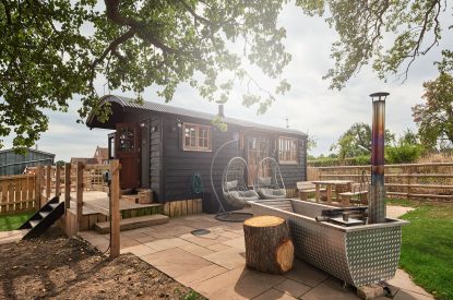 The exterior of the shepherd's hut with the wood-fired Swedish Hikki hot tub at The Hangout Hut, Worcestershire 