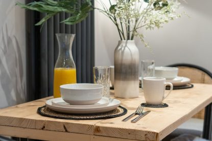 The dining room table with cutlery and crockery laid out at Pilgrim Cottage, Cheshire