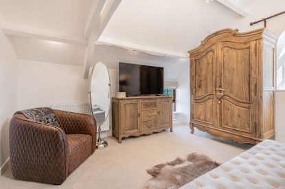 A single armchair and smart TV in a king-size bedroom at Rose Walls, Lake District 