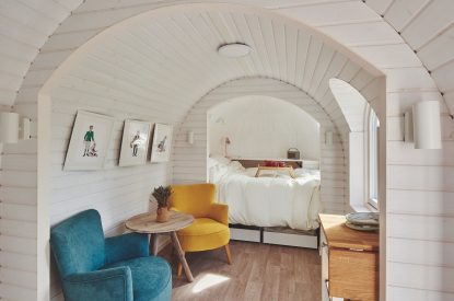 A blue and yellow armchair and double bed at Orchard Snug, Somerset