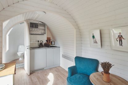 A blue armchair and the kitchenette at Orchard Snug, Somerset