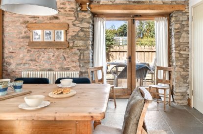 The dining table with doors onto the patio at Chapel Cottage, Pembrokeshire