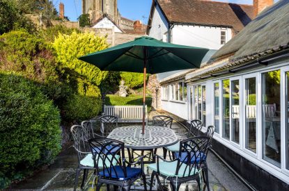The patio with a dining table at parasol at Thatch Corner, Somerset