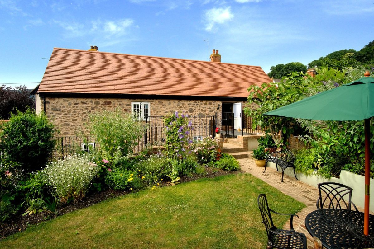 The garden with a dining table overlooking the exterior of Exmoor Barn, Somerset
