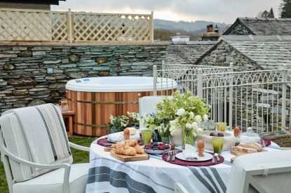The outdoor dining table and hot tub at Beatrix Cottage, Lake District