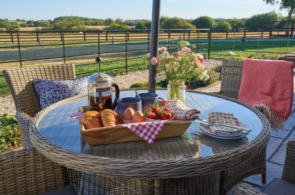 The outdoor rattan table and chairs with a hamper at Stable Barn, Cotswolds