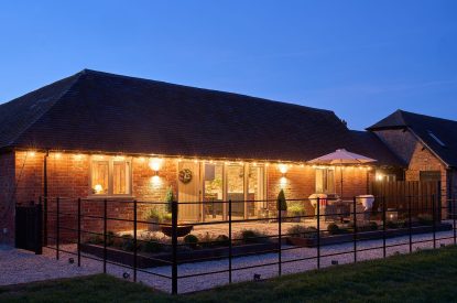 The exterior of the barn at night with the fairy lights switched on at Stable Barn, Cotswolds