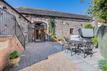 The private patio with a hot tub and a dining table and chairs at Rose Walls, Lake District