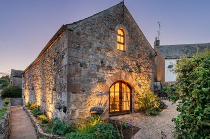 The exterior of the cottage at night at Rose Walls, Lake District