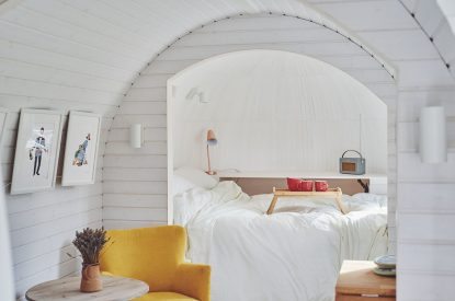 A yellow armchair and double bed at Orchard Snug, Somerset