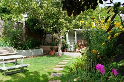 The garden with a stone path leading to a summer house at Sweet Shop Cottage, Somerset
