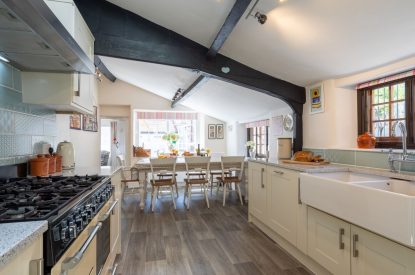 The galley kitchen with a large dining table at Sweet Shop Cottage, Somerset