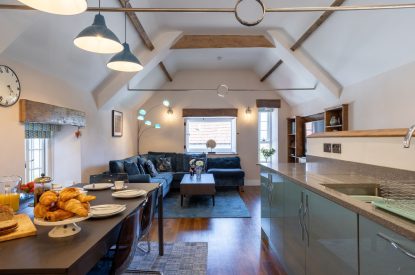 The kitchen and living room with a vaulted ceiling and beams at Exmoor Barn, Somerset
