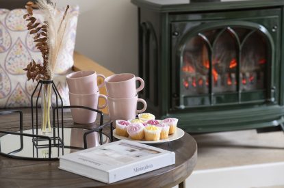 A coffee table with magazines in front of the log burner at Farmyard Cottage, Wiltshire