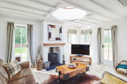 The living room with a log burner and views over the garden at Osborne Lodge, Herefordshire
